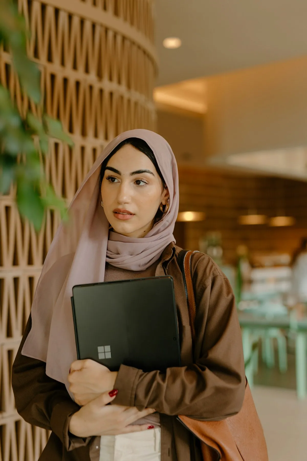 A professional carrying a laptop through a modern office reception