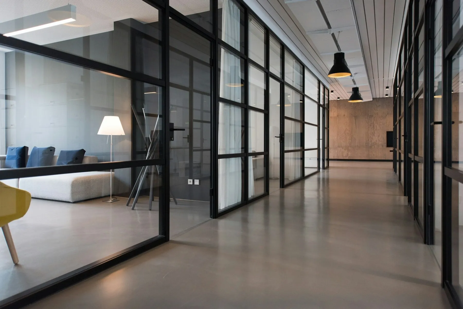 A modern office corridor with black steel framed glass partitions